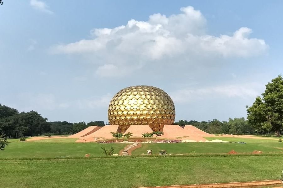 The golden Matrimandir in Auroville seen across green lawns