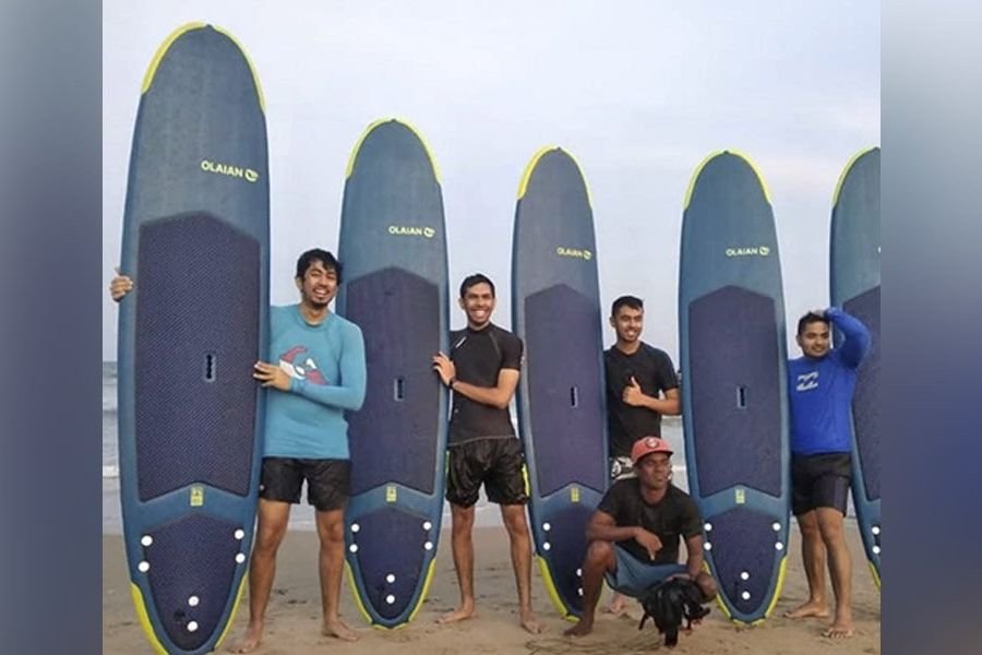 Surfers carrying boards into the waves on a Pondicherry beach